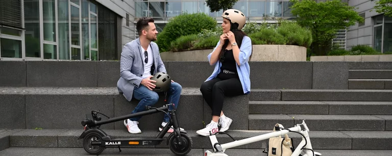 Zwei Stundenten auf einer Treppe mit Trittbrett E-Scootern