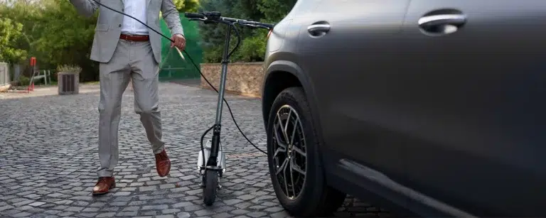 Geschäftsmann mit E-Scooter und Auto