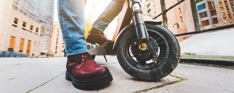 Startseite 23 Nahaufnahme von einem E-Scooter-Reifen und einem roten Stiefel