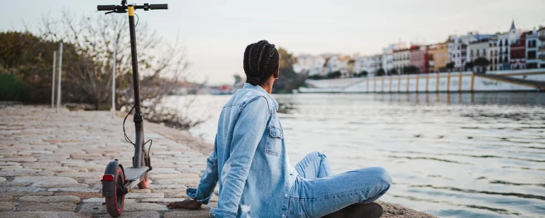 Startseite 33 Mann sitzt am Wasser mit seinem E-Scooter