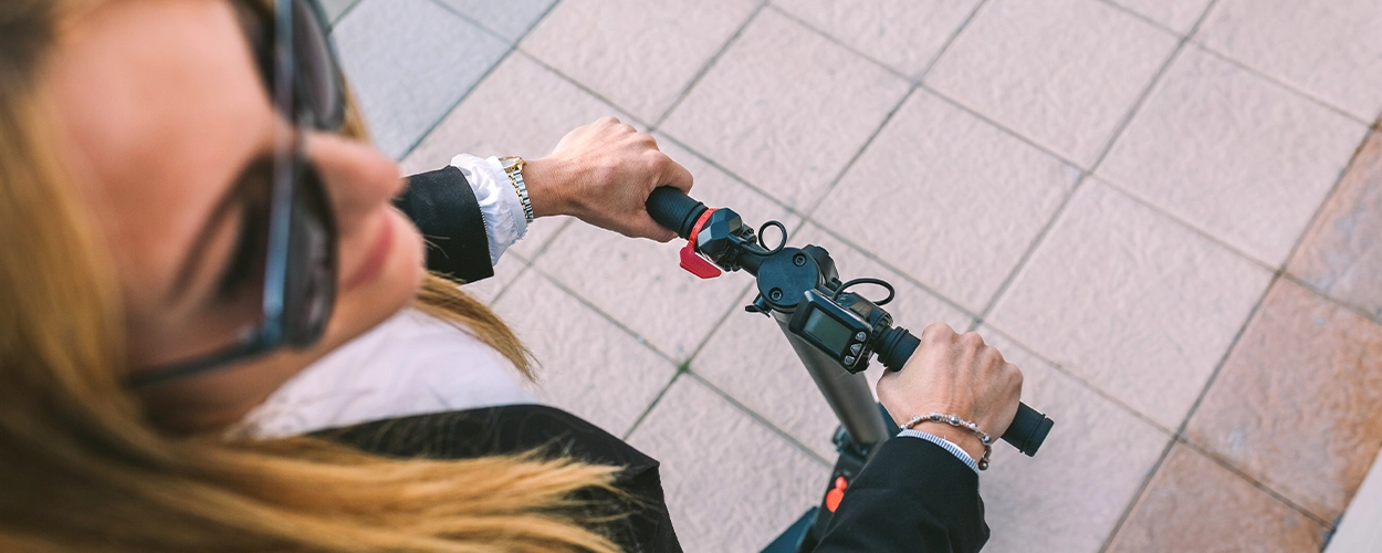 Sicht von oben auf eine Frau die auf einem E-Scooter steht
