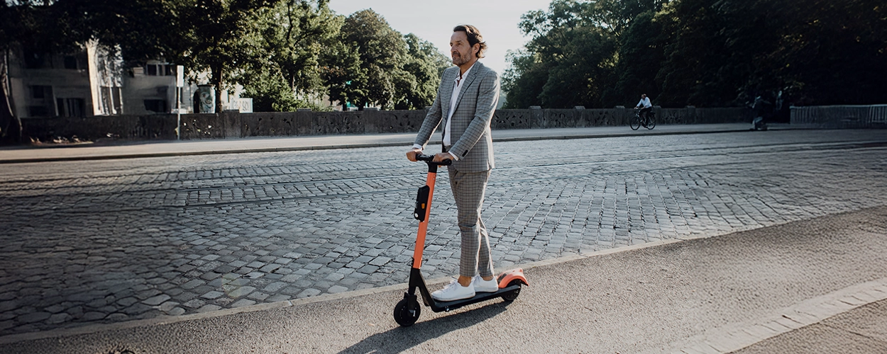 Mann im Anzug auf einem E-Scooter