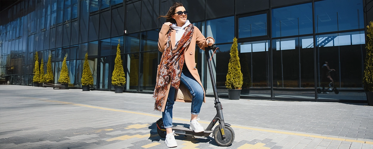 Frau steht auf einem E Scooter mit einem Fuß am Boden