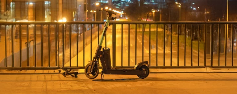 E-Scooter bei Nacht über einer Straße, auf einer Brücke